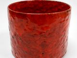 un gobelet rouge posé sur une surface blanche