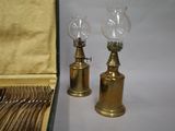 pair of antique brass oil lamps in a case on a white background