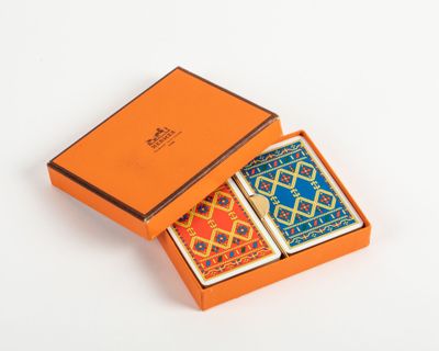 an orange box with two playing cards in it on a white surface