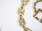 a gold necklace and a bracelet on a white surface