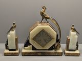 une horloge surmontée d'un oiseau, à côté de deux bougies