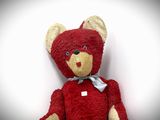 a red teddy bear with a white bow on it ' s neck
