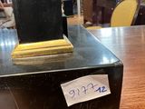 a black clock on a wooden table with a note on it