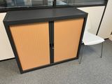 a cabinet with a door and a chair in front of it