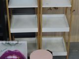 three shelves with lipstick prints on them and a pink stool