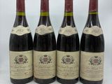quatre bouteilles de vin sont alignées sur une surface blanche