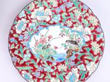 une assiette rouge décorée d'un oiseau et de fleurs