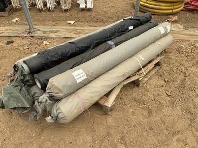 de nombreux rouleaux de tissu posés par terre à côté d'une borne d'incendie