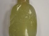 a green glass bottle with a brown lid on a white surface