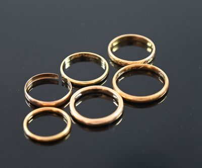 five gold rings sitting on top of a black surface