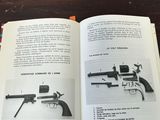 an open book with a picture of a gun and a gun on a table