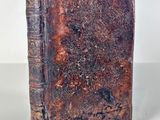 an old book sitting on top of a table next to a white wall