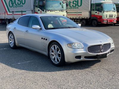 a silver maserat parked in a parking lot next to a truck