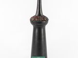a black vase sitting on top of a table next to a green card