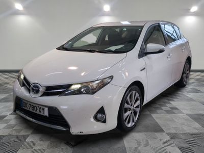 La Toyota Corolla blanche est garée dans une pièce au sol à carreaux.