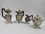 three silver plated teapots and a coffee pot on stands