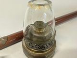 a small glass jar with a wooden handle next to a metal tray with a candle on it
