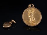 gold plated medal with a heart shaped charm on a black surface