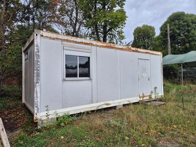 une photo d'un petit bâtiment blanc dans les bois