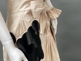 an image of a mannequin wearing a beige dress with a black bow