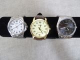 three watches are sitting on a black display stand on a white surface