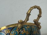 a blue and gold vase with a handle on a table