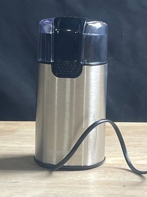 un moulin à café argenté et noir posé sur une table en bois