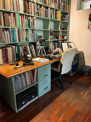 a desk with a chair in front of a bookshelf filled with books