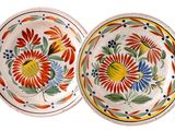 two plates with colorful designs on them are sitting on a white surface