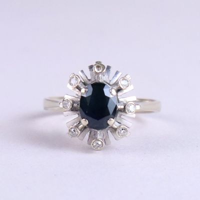 gros plan d'une bague avec un saphir bleu entouré de diamants blancs