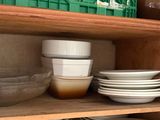 many plates and bowls on the shelves in the kitchen