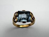 a close up of a gold ring with a blue topaz stone