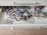 a drawer full of glasses and other items on the table