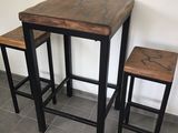 deux tabourets et une table dans une pièce où est accroché un tableau au mur