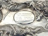 a silver plate with a picture of a dragon and a dragon on it