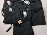 trois paires de pantalons noirs, encore étiquetés, posées sur une table