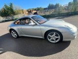La Porsche 911 argentée est garée sur le parking.