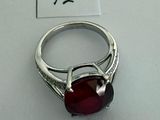 silver ring with a red stone on top of a white surface