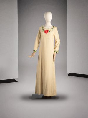 une photo d'un mannequin portant une robe beige ornée de fleurs rouges