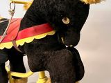 a black horse with a red and yellow harness on a yellow tricycle