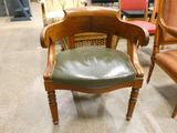 a wooden chair with a green leather seat in a room