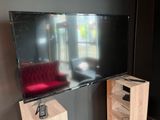 un téléviseur à écran plat posé sur un support dans le coin d'une pièce