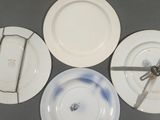 four white plates with blue and white designs on them with a knife stuck in the middle of the plate