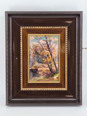 an oil painting of a river and trees in a wooden frame