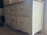 a white dresser in a room with a tv on the wall