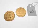 two gold coins sitting next to each other on a white surface