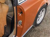 an orange car with its door open on the side of the road