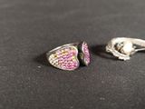 two rings with pink and green stones on them on a black surface