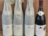 three bottles of wine sitting on a shelf next to a bottle of wine