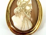 gold - plated brooch depicting a bust of a man wearing a hat and holding a cane